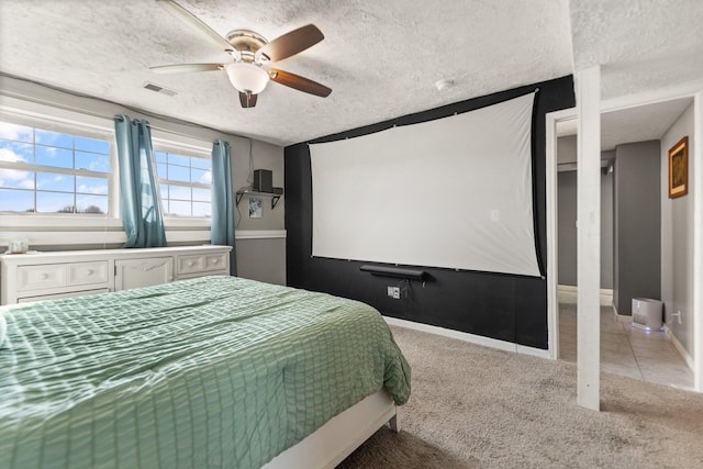 carpeted bedroom featuring baseboards, visible vents, a textured ceiling, and a ceiling fan