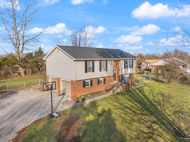 bi-level home featuring fence, driveway, an attached garage, a front lawn, and brick siding