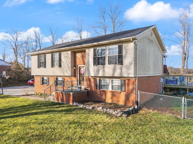 split foyer home with brick siding, a gate, a front yard, and fence