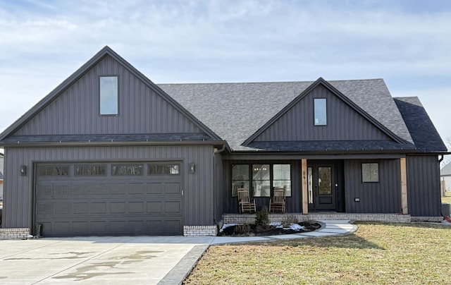 modern farmhouse style home with an attached garage, covered porch, driveway, roof with shingles, and a front yard