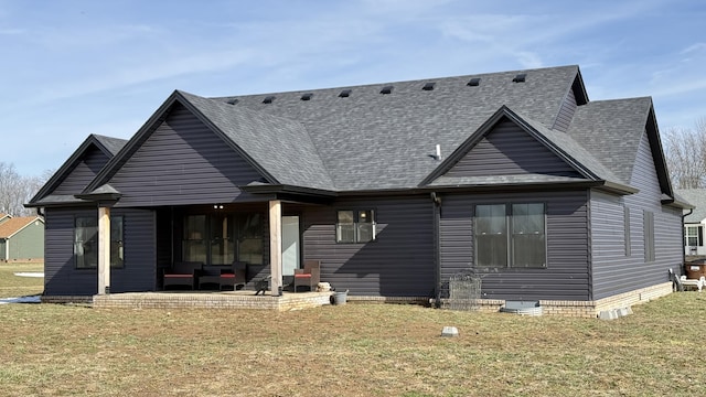 back of property with a shingled roof, a patio area, and a yard