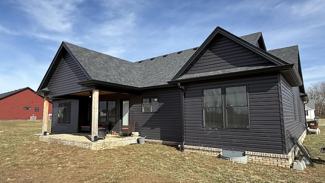 view of front of property with a front yard, a patio area, and roof with shingles