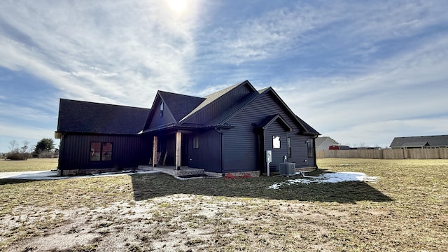 view of front of property featuring board and batten siding, cooling unit, fence, and a front yard