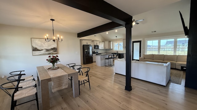 dining space with visible vents, lofted ceiling with beams, light wood finished floors, and an inviting chandelier