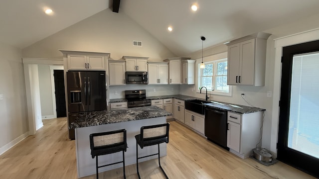 kitchen with visible vents, a kitchen island, black appliances, pendant lighting, and a sink