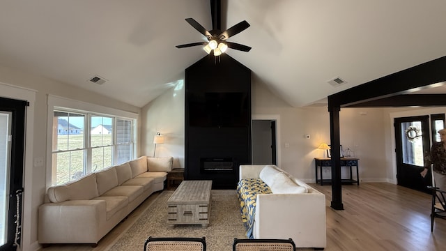 living area featuring a ceiling fan, light wood-type flooring, visible vents, and lofted ceiling with beams