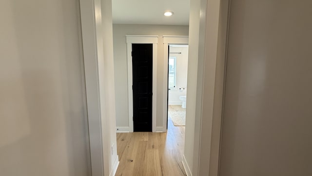 hall with baseboards and light wood finished floors