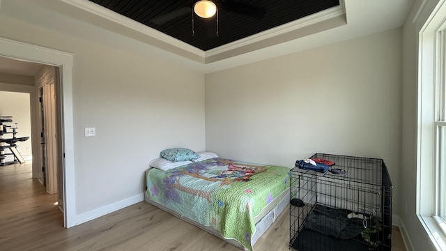 bedroom with a raised ceiling, light wood-style floors, ornamental molding, wood ceiling, and baseboards