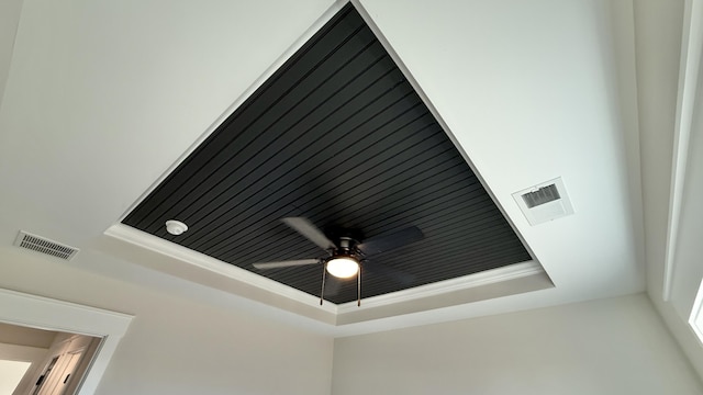 room details with a tray ceiling, visible vents, and ceiling fan