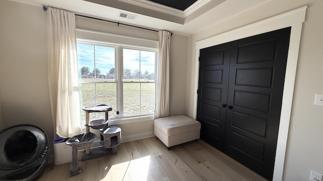 foyer entrance featuring light wood-type flooring, visible vents, crown molding, and baseboards