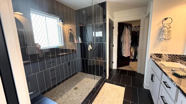 bathroom with a spacious closet, tile patterned flooring, vanity, and a shower stall