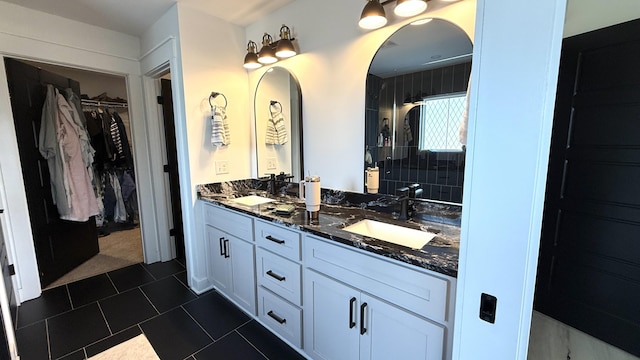 bathroom with a sink, double vanity, and a walk in closet