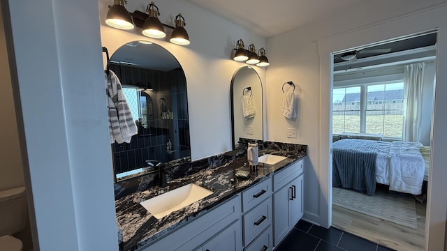 ensuite bathroom featuring connected bathroom, tile patterned flooring, a sink, and double vanity