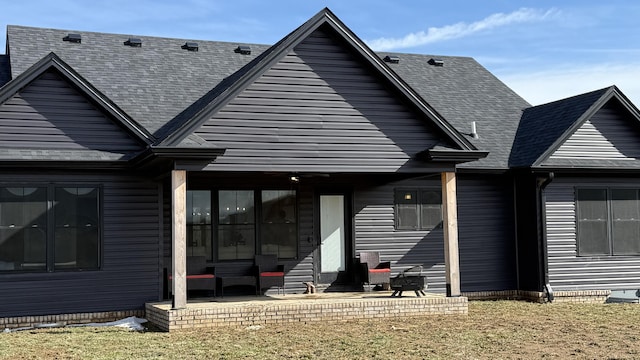 back of house with roof with shingles, a patio, and a lawn