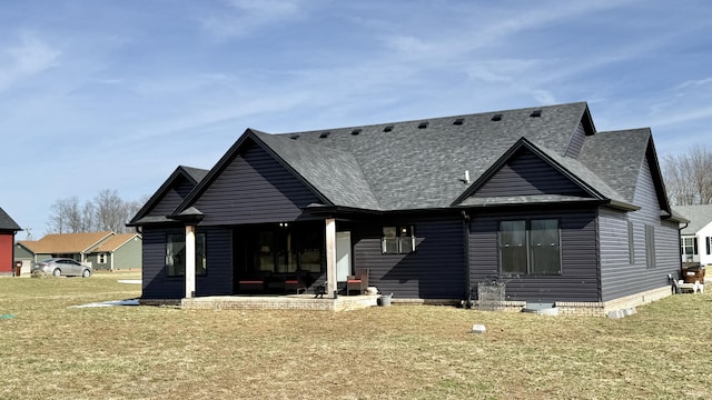 rear view of house featuring a shingled roof, a lawn, and a patio