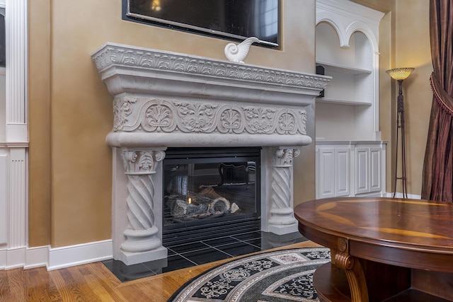 interior details featuring a fireplace with flush hearth, baseboards, and wood finished floors