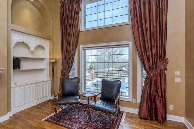 living area featuring baseboards, plenty of natural light, wood finished floors, and built in features