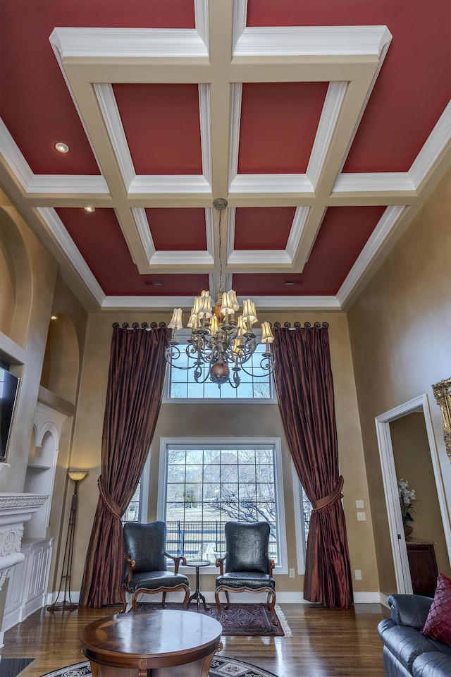 living area with a high ceiling, built in features, coffered ceiling, and crown molding