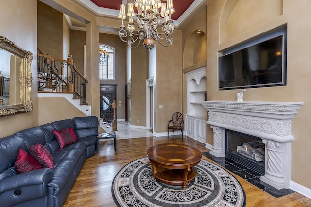 living area featuring built in shelves, stairway, a fireplace with flush hearth, ornamental molding, and wood finished floors