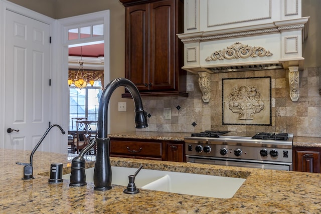 kitchen featuring light stone counters, a notable chandelier, range, and decorative backsplash