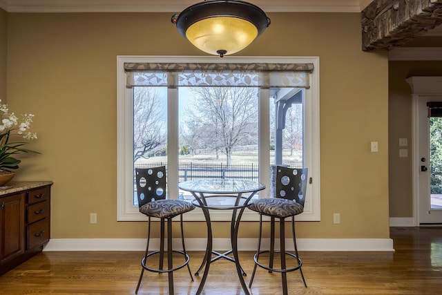 dining room featuring crown molding, baseboards, and wood finished floors