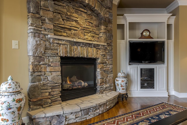 living area featuring a stone fireplace, ornamental molding, wood finished floors, and baseboards