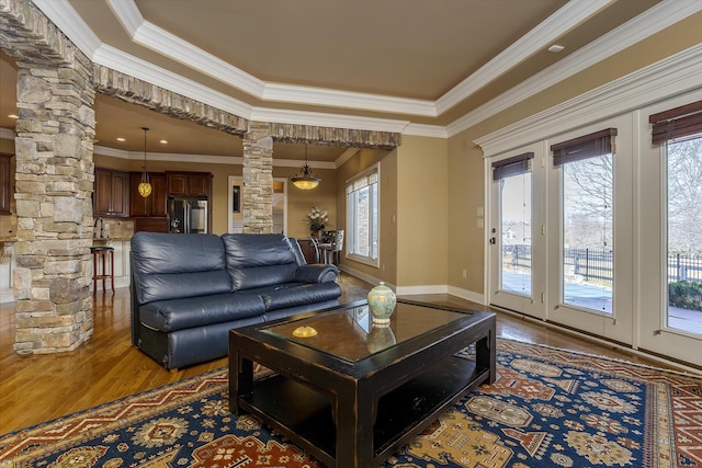 living room featuring wood finished floors, decorative columns, and crown molding