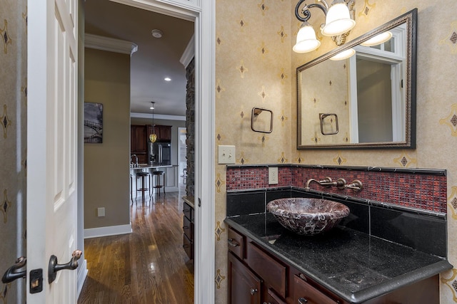 bathroom featuring crown molding, baseboards, wood finished floors, and vanity