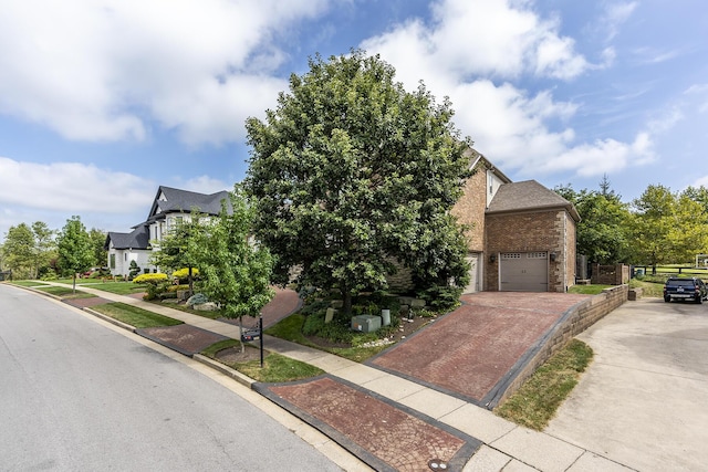 view of front of property with a garage, driveway, brick siding, and fence