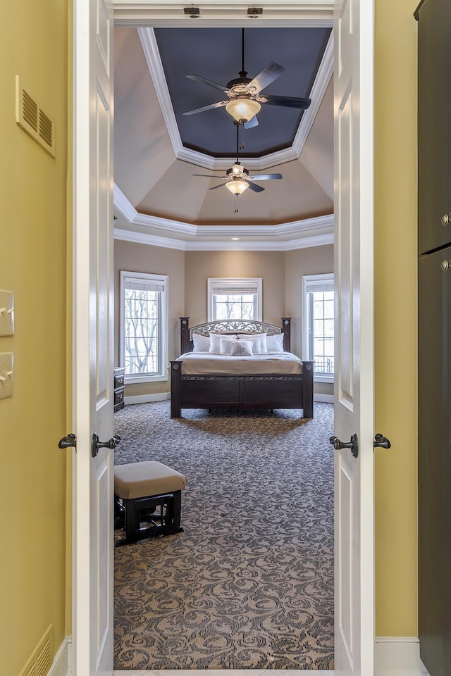 bedroom featuring carpet, a raised ceiling, visible vents, and crown molding