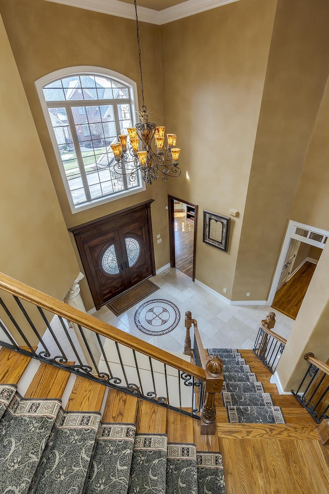 entryway with baseboards, stairs, a towering ceiling, and a notable chandelier