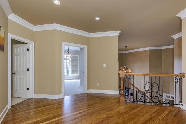 unfurnished room with a chandelier, wood finished floors, and crown molding