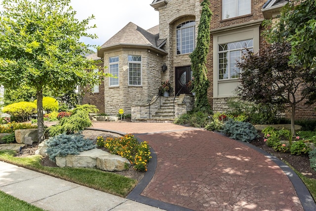 view of front of property with stone siding and roof with shingles