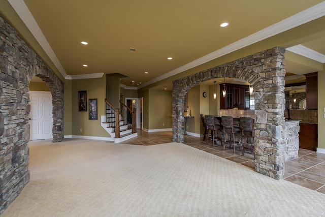 interior space featuring carpet floors, arched walkways, decorative columns, a dry bar, and stairs