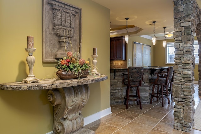 bar with a tray ceiling, crown molding, tasteful backsplash, ornate columns, and tile patterned floors