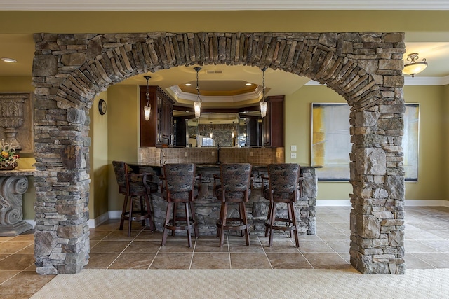 bar featuring arched walkways, ornate columns, and crown molding