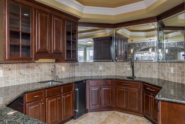 kitchen with crown molding, dark stone counters, and a sink