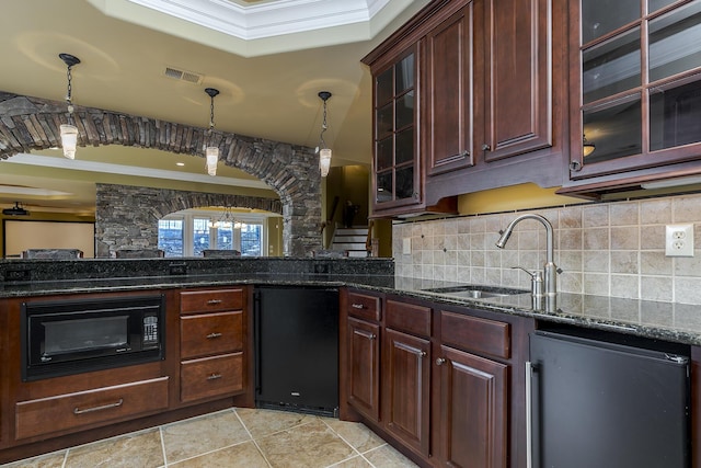 kitchen with refrigerator, a sink, hanging light fixtures, decorative backsplash, and dark stone countertops