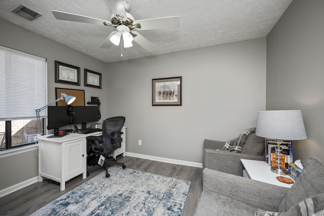 office featuring dark wood-type flooring, a ceiling fan, visible vents, and baseboards