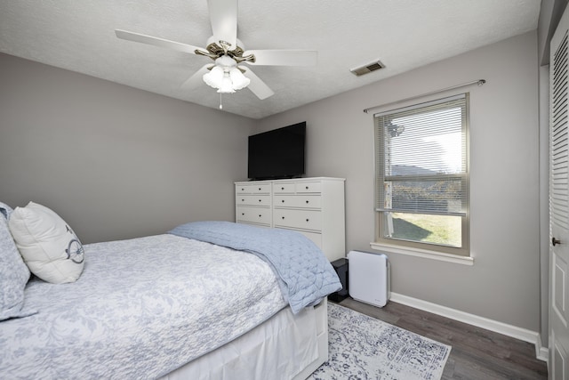 bedroom with baseboards, a textured ceiling, visible vents, and wood finished floors