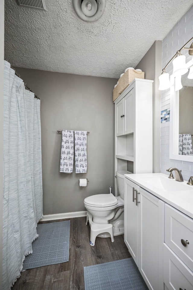 full bathroom featuring a textured ceiling, toilet, wood finished floors, vanity, and baseboards