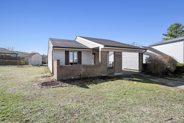 view of front of property featuring a shingled roof, fence, a front lawn, and brick siding