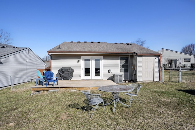 rear view of property featuring a yard, a shingled roof, a wooden deck, and fence