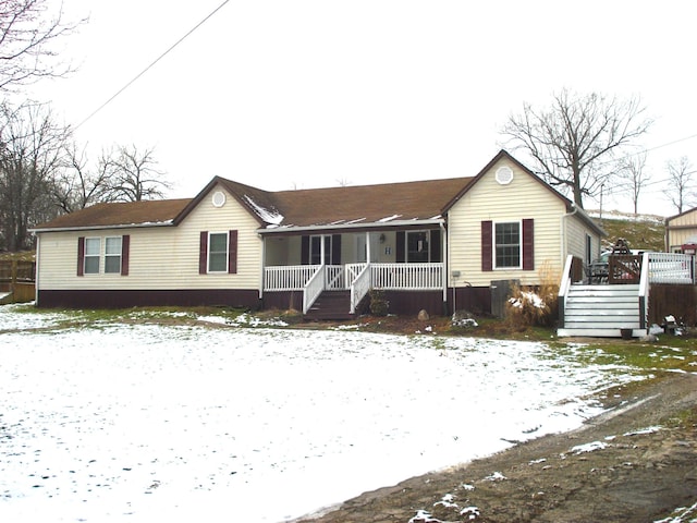 snow covered rear of property featuring covered porch