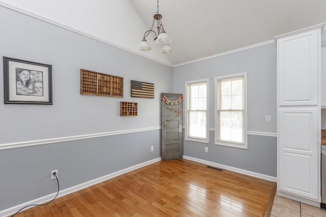 unfurnished room featuring vaulted ceiling, visible vents, light wood-style flooring, and baseboards