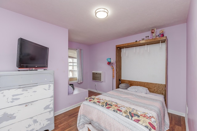 bedroom featuring baseboards, wood finished floors, and a wall mounted AC