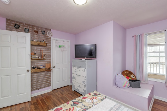 bedroom with dark wood-style floors, a textured ceiling, and baseboards