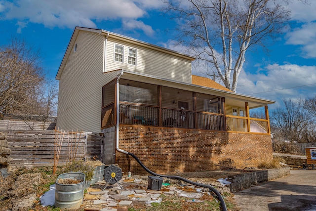 view of side of home featuring a sunroom and fence