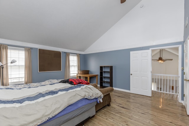 bedroom with high vaulted ceiling, light wood finished floors, and baseboards