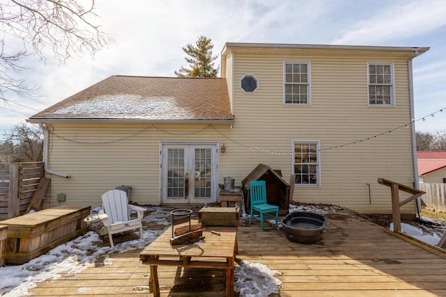 snow covered property featuring a fire pit, french doors, a shingled roof, and a wooden deck